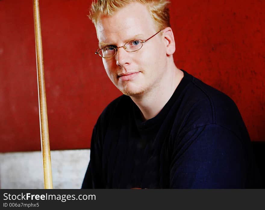 Blond man holding a pool cue. Blond man holding a pool cue