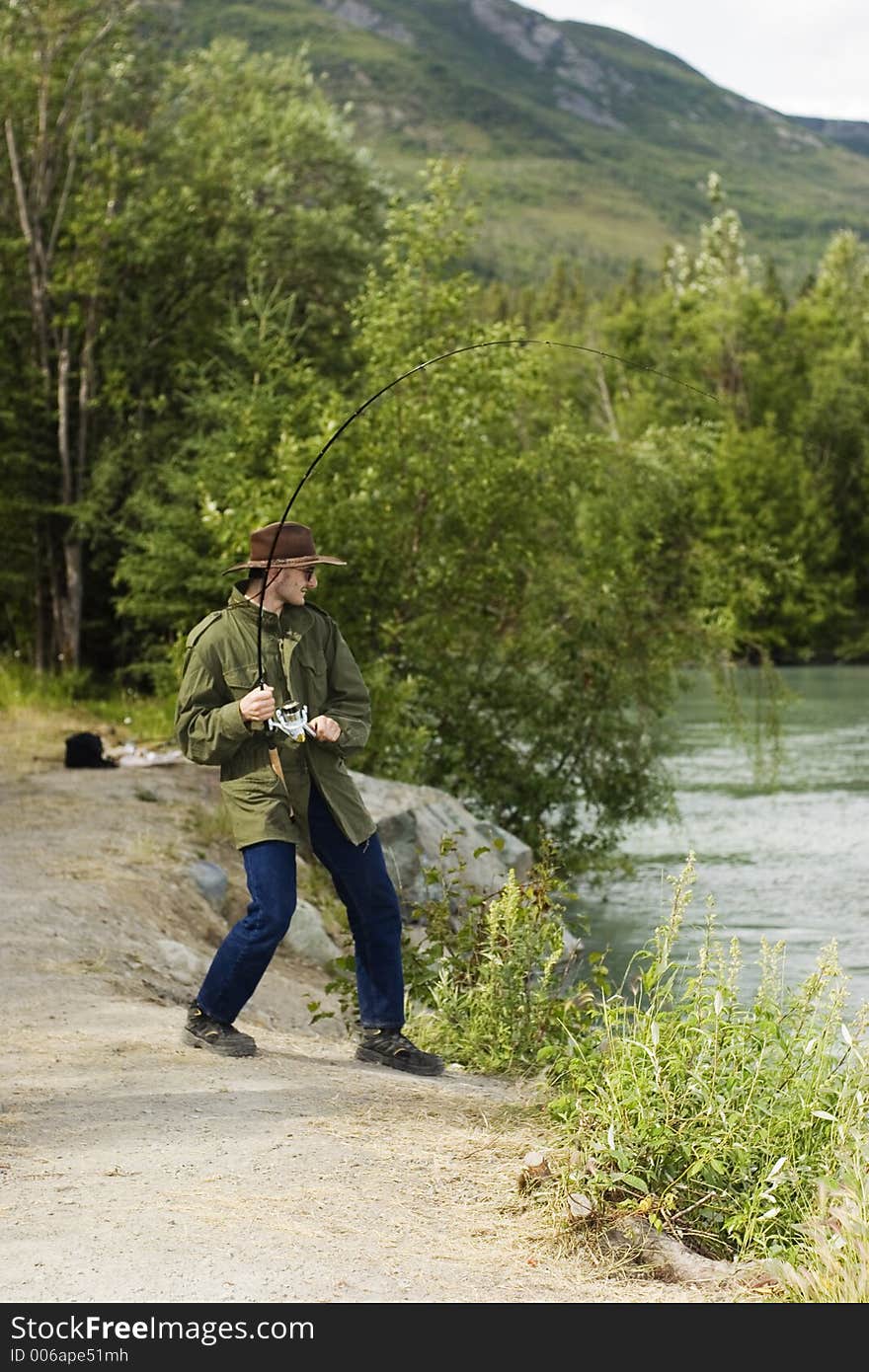 Fisherman playing big salmon - chinook or king salmon. Fisherman playing big salmon - chinook or king salmon