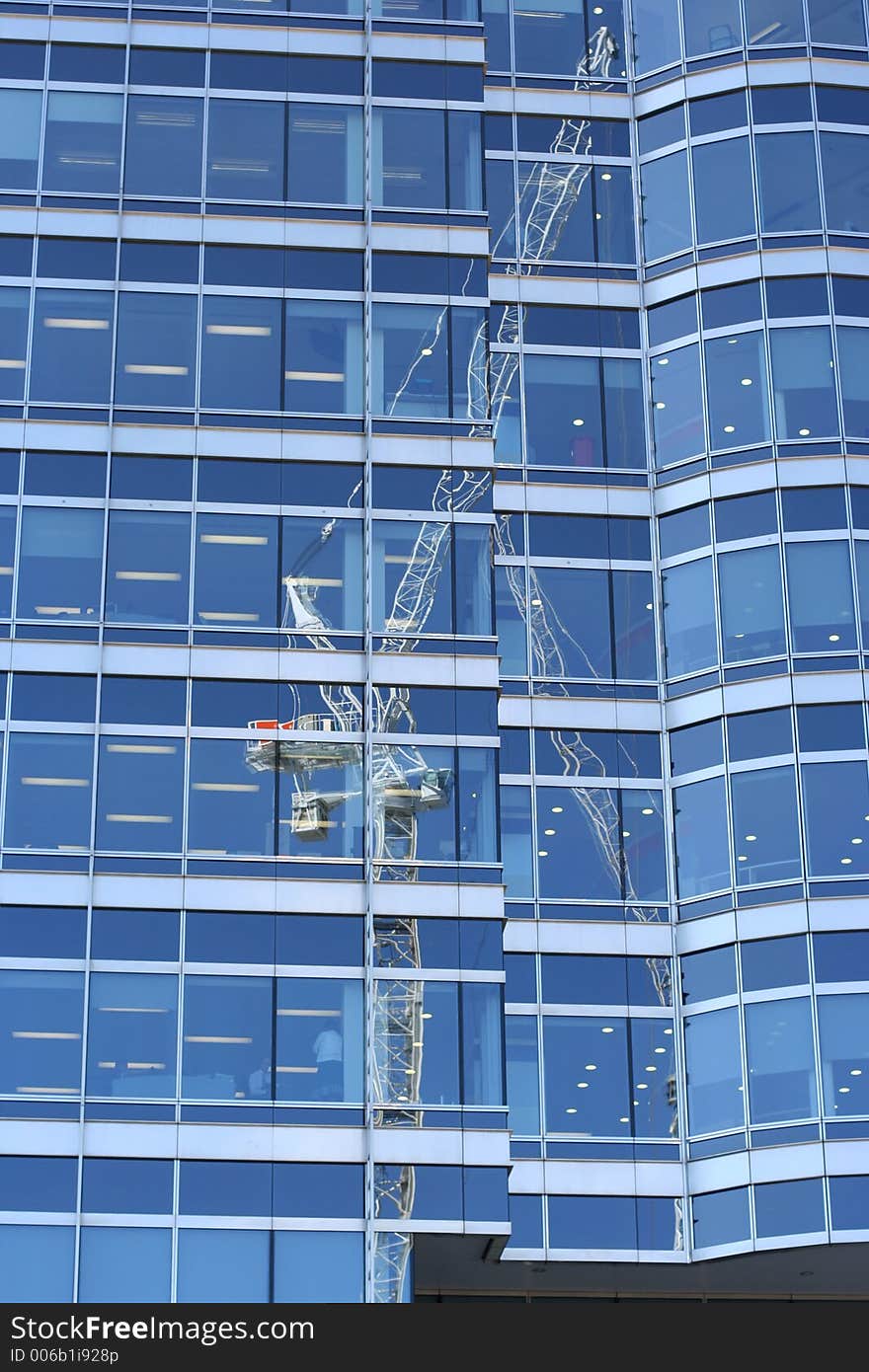 Cranes reflected in mirrored office block in docklands london. Cranes reflected in mirrored office block in docklands london