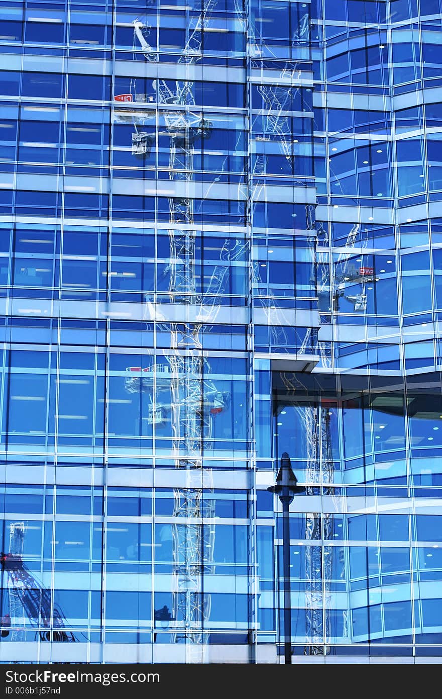 Cranes reflected in mirrored office block in docklands london. Cranes reflected in mirrored office block in docklands london