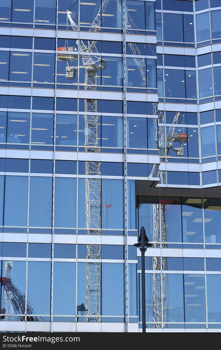 Cranes reflected in mirrored office block in docklands london. Cranes reflected in mirrored office block in docklands london