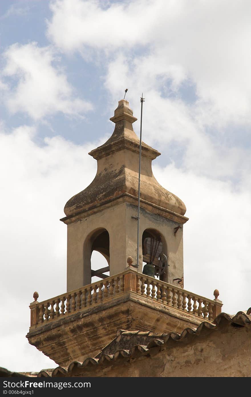 Old bell tower against blue sky with white cloud