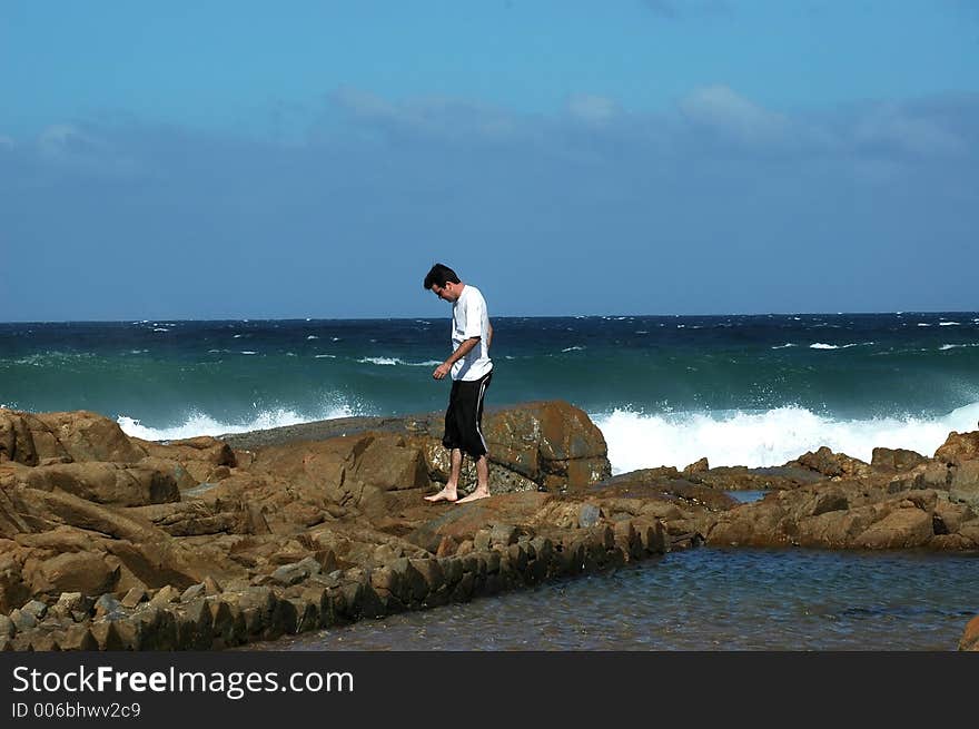 Man walking on the rocks at the beach. Man walking on the rocks at the beach