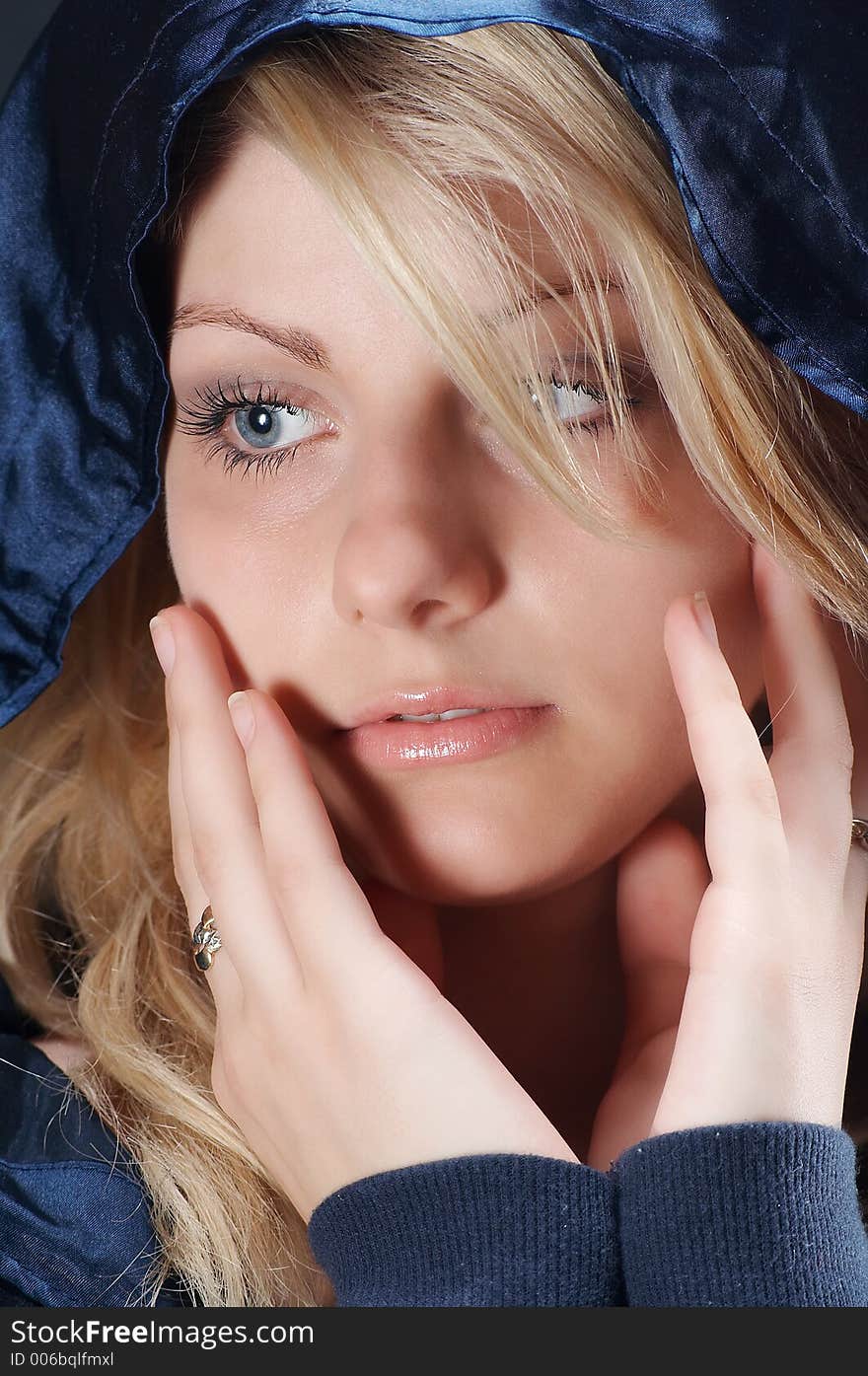 Blonde girl looking, with a dark blue blouse and a hood on his head, close-up