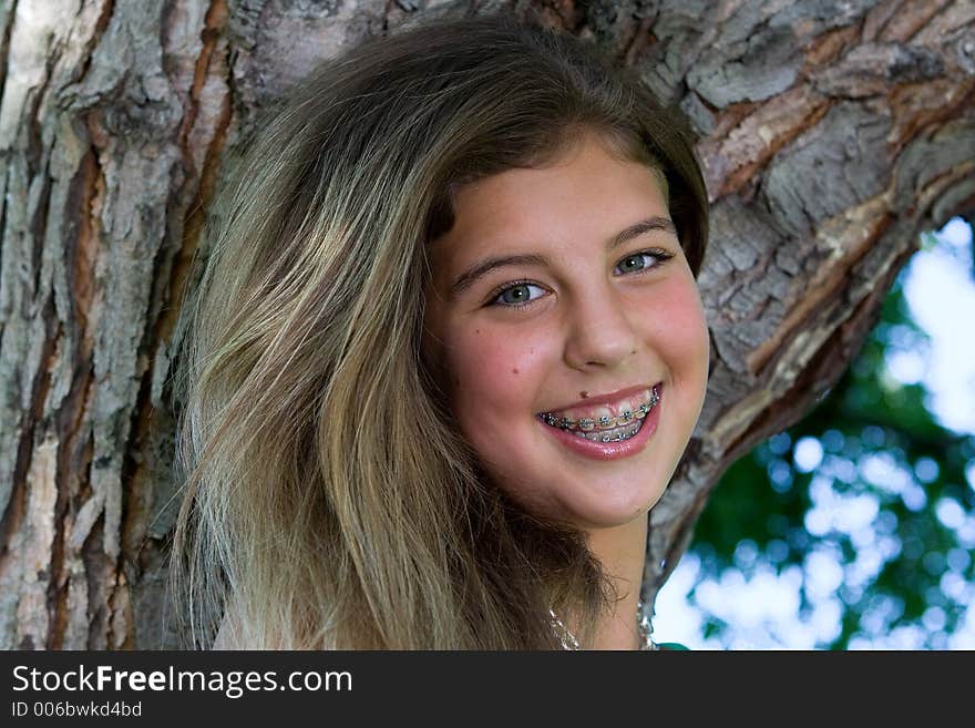 Pretty teenage girl with braces smiling in front of a tree. Pretty teenage girl with braces smiling in front of a tree.