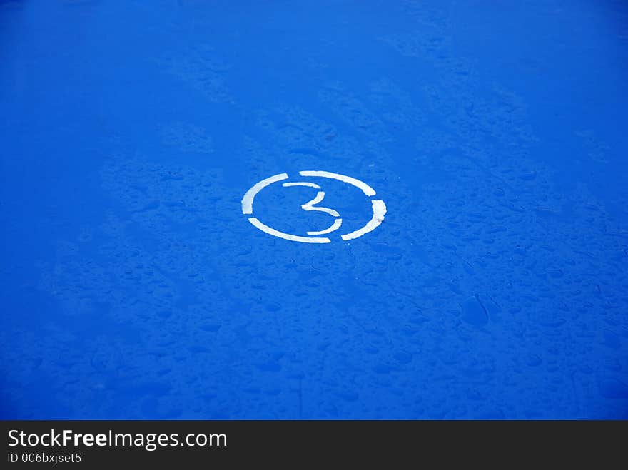 Figure of three in a white circle on a dark blue wet surface. Figure of three in a white circle on a dark blue wet surface