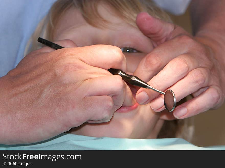 A young boy at the dentists, dentist taking a look into his mouth using various tools. A young boy at the dentists, dentist taking a look into his mouth using various tools