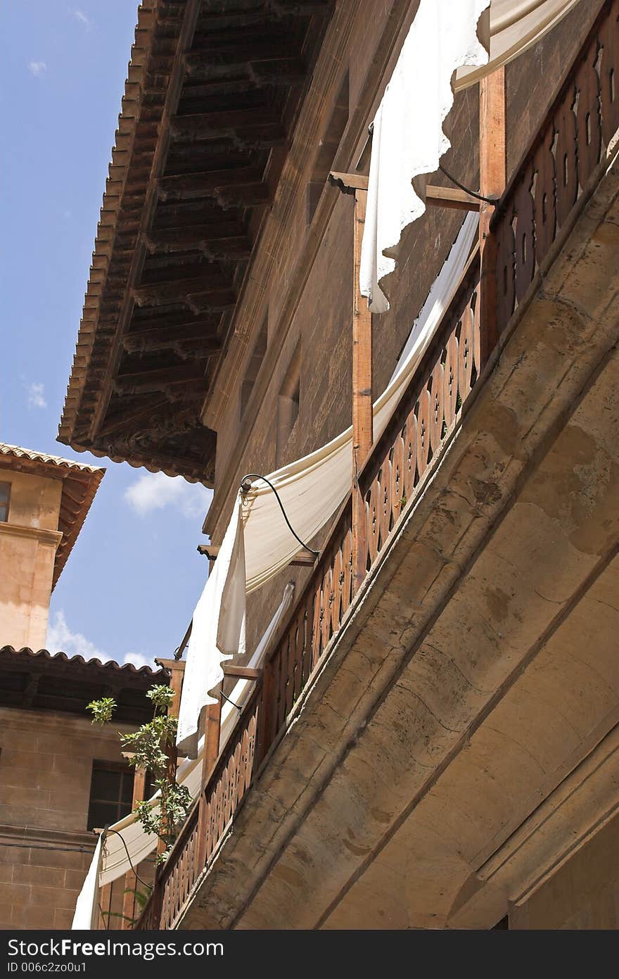 White linen window shades drapped from roof of old spanish home