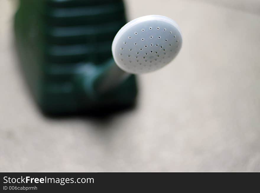 A green watering can with only the head in focus