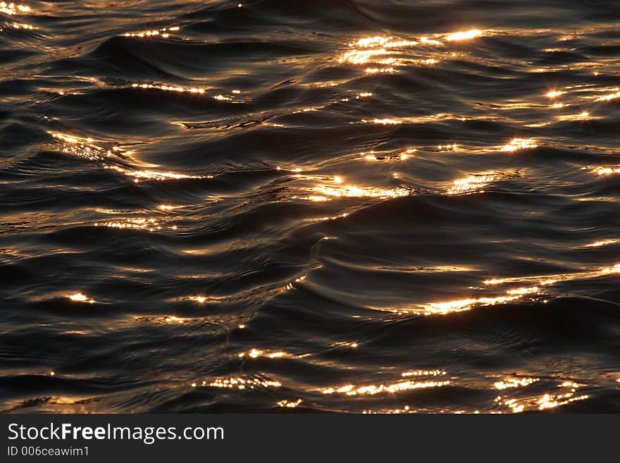 Golden sunlight reflects off dark calm waters. Golden sunlight reflects off dark calm waters.