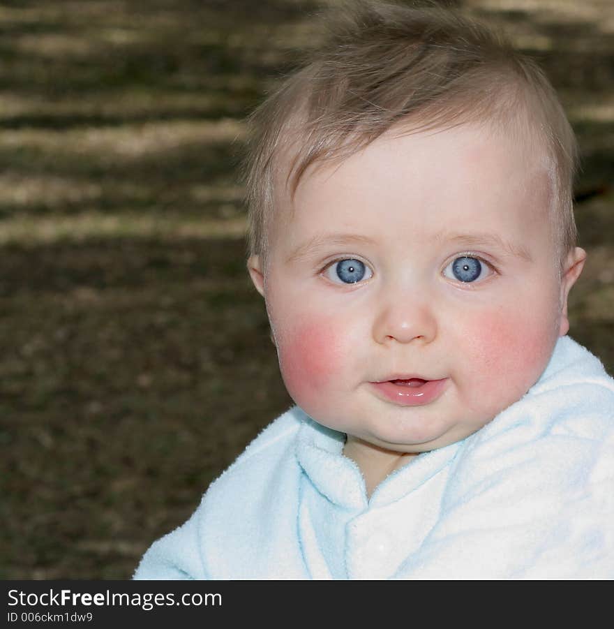 Baby boy with amazing blue eyes sitting in the park. Baby boy with amazing blue eyes sitting in the park.