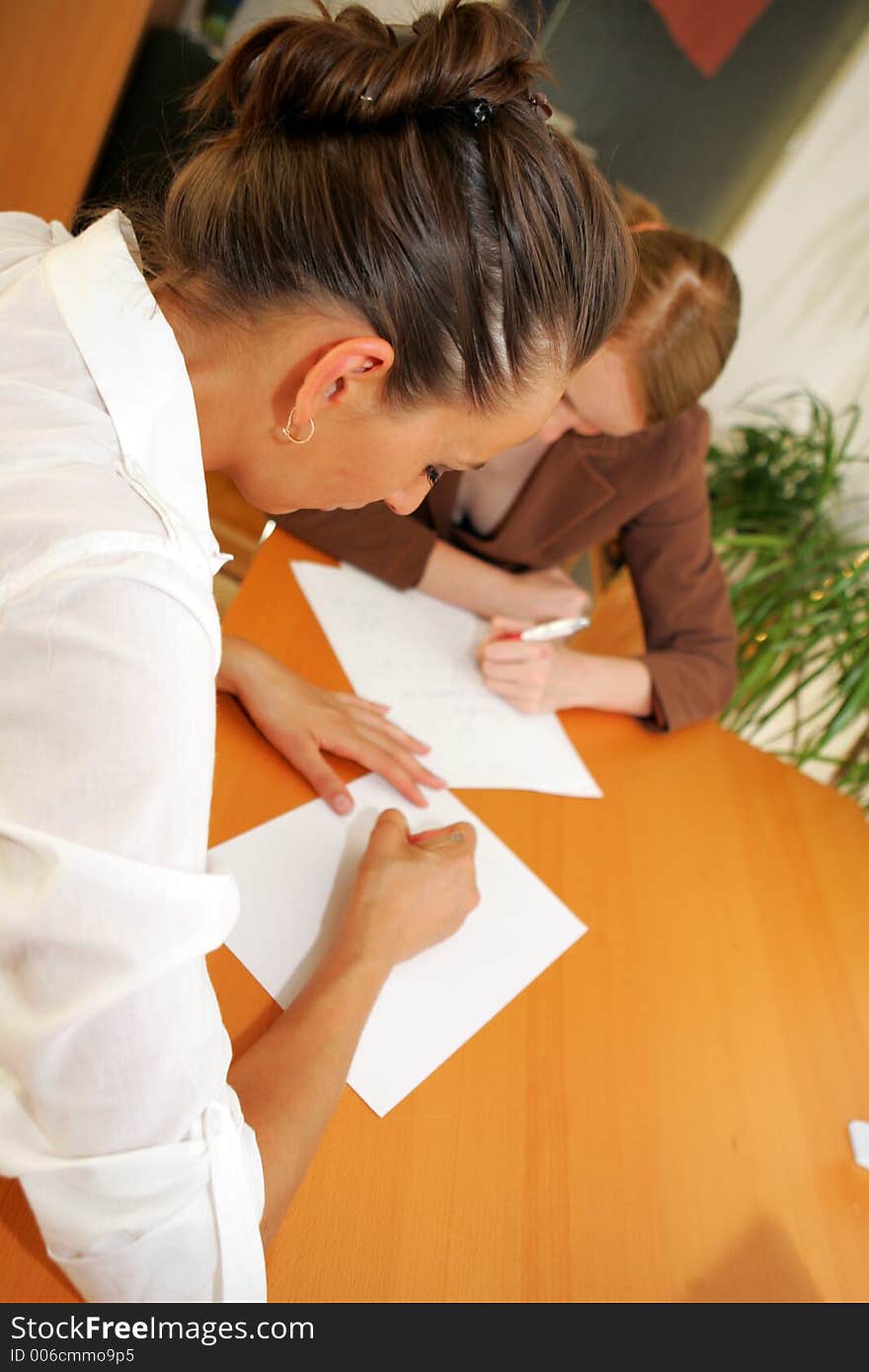 Two business women taking notes in the office. Two business women taking notes in the office