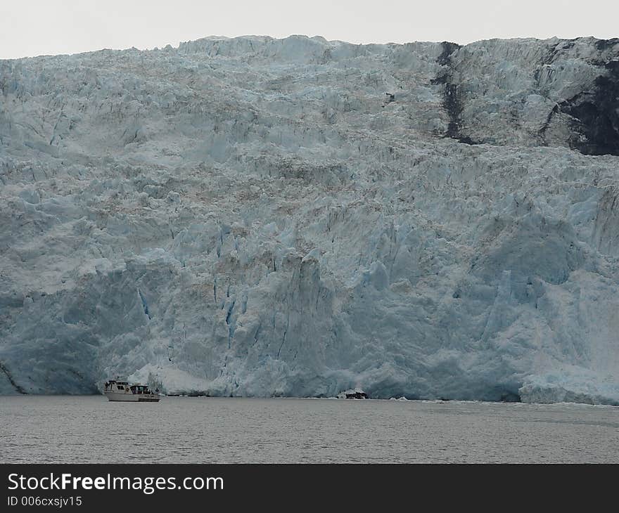 Small tourist boat at the foot of a glacier in Alaska. Small tourist boat at the foot of a glacier in Alaska.