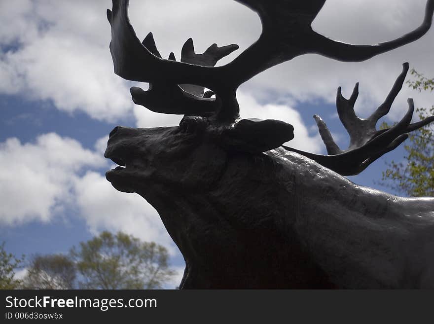 Statue of a caribou silloutted on the sky.