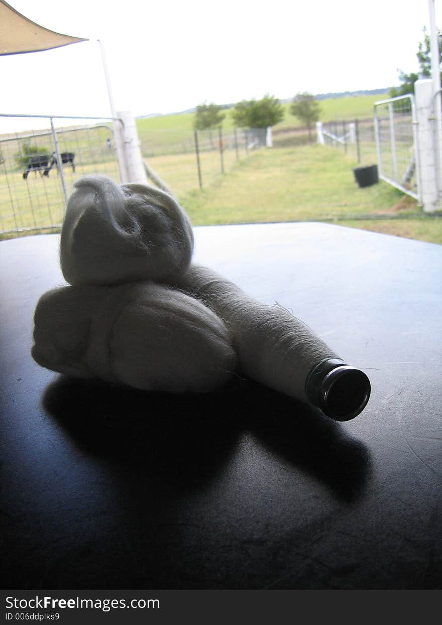 Backdrop of farm with Alpaca roving and spindle of thread on a table