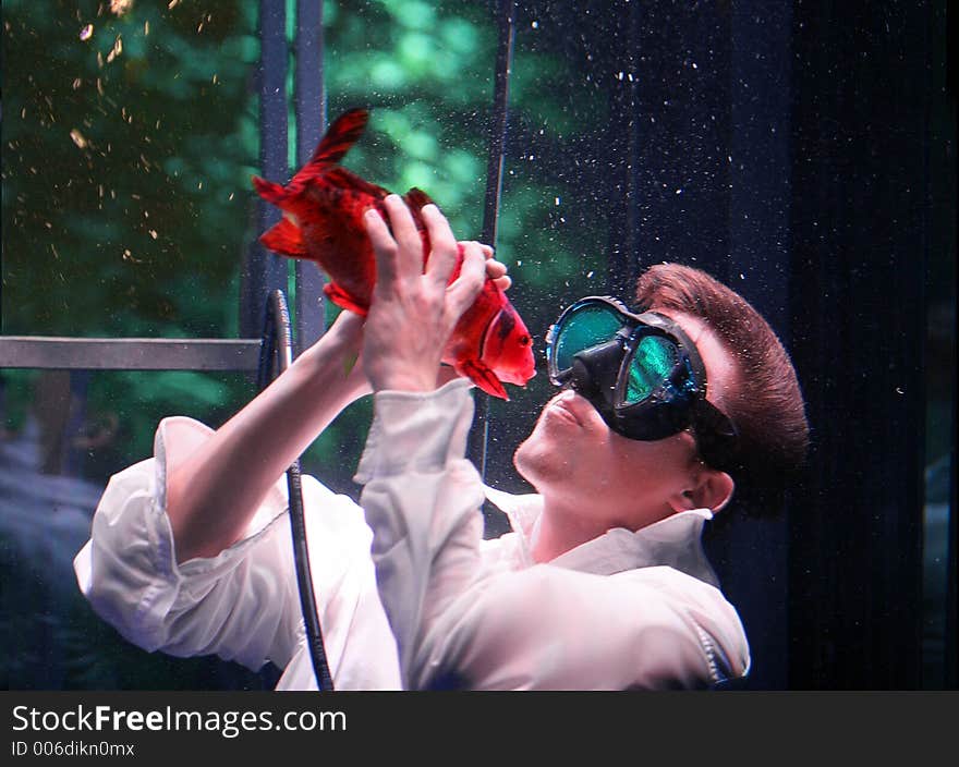 Young man kissing fish underwater