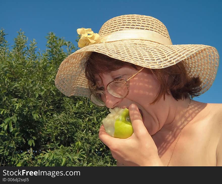 Girl eats apple on nature