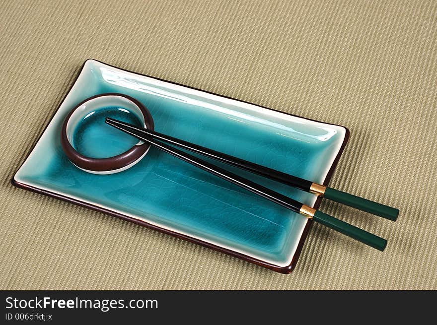 Plate, dipping bowl and chop sticks on green mat