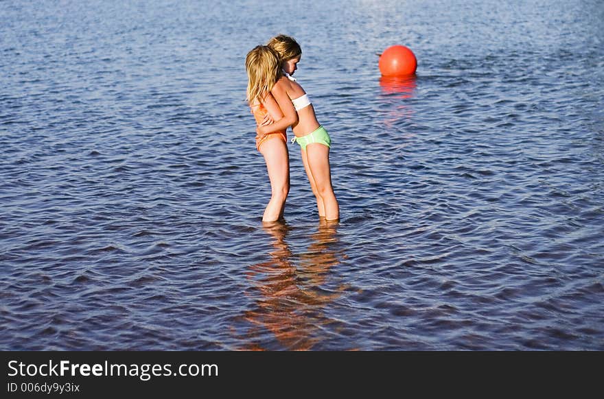 Two girls in the water hugging because they are cold. Two girls in the water hugging because they are cold