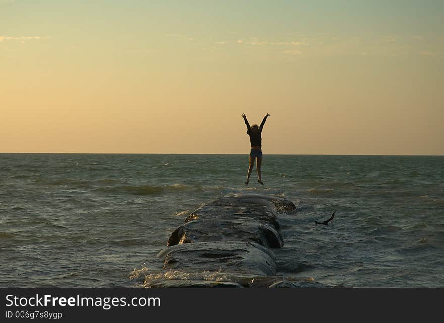 Girl jumping on a rock at sunset in Holbox, Caribbean, Mexico