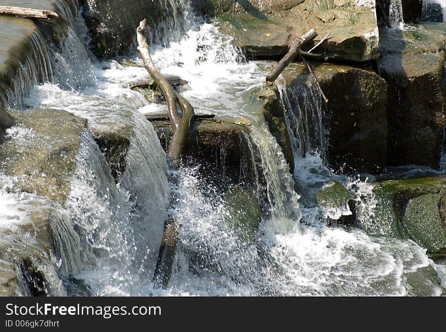 A waterfall with several levels of rocks and a piece of wood sticking up out of water. Water frozen with fast shutter speed. A waterfall with several levels of rocks and a piece of wood sticking up out of water. Water frozen with fast shutter speed