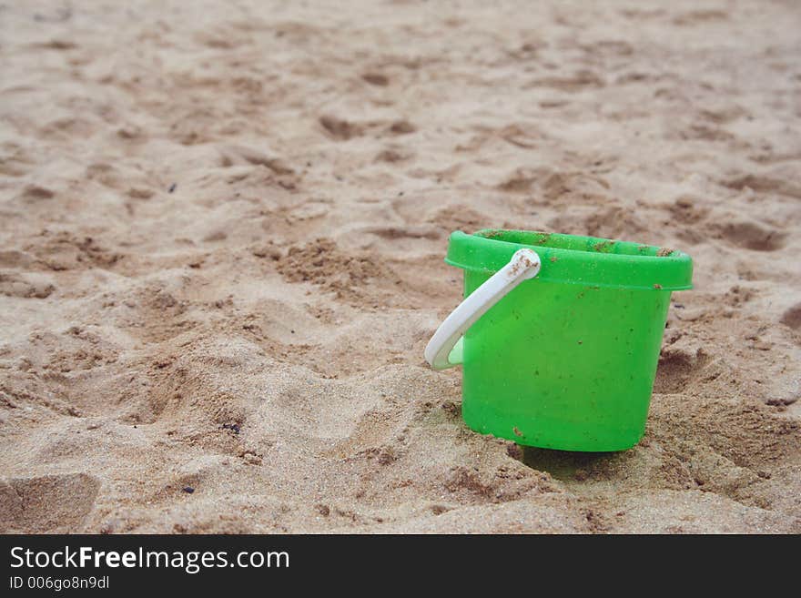 Green bucket left on the beach