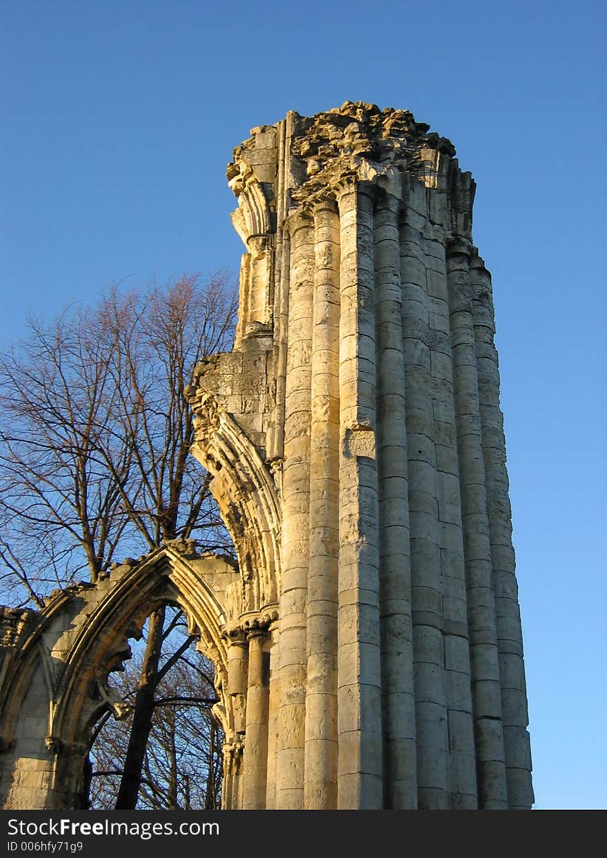 Ruined church pillar and archway in early evening light.