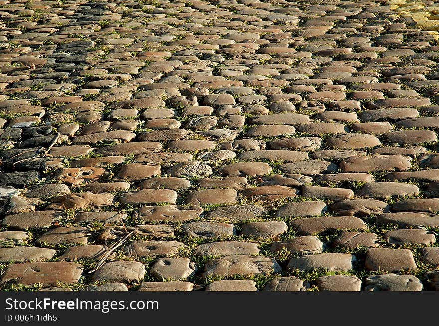 Detail of a sunny cobbled road in autumn. Detail of a sunny cobbled road in autumn