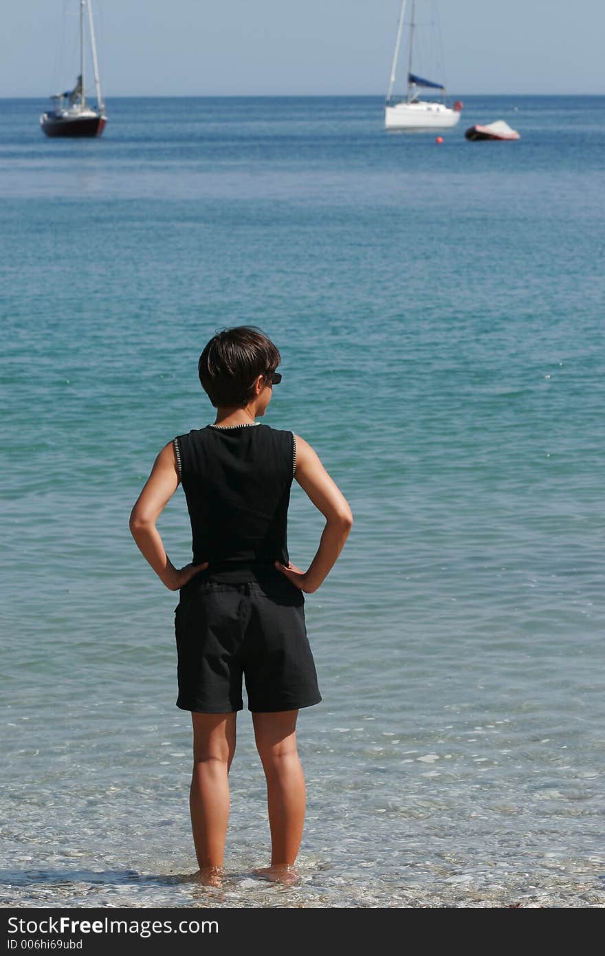 Femme au bord d'une plage regardant au loin les bateaux. Femme au bord d'une plage regardant au loin les bateaux