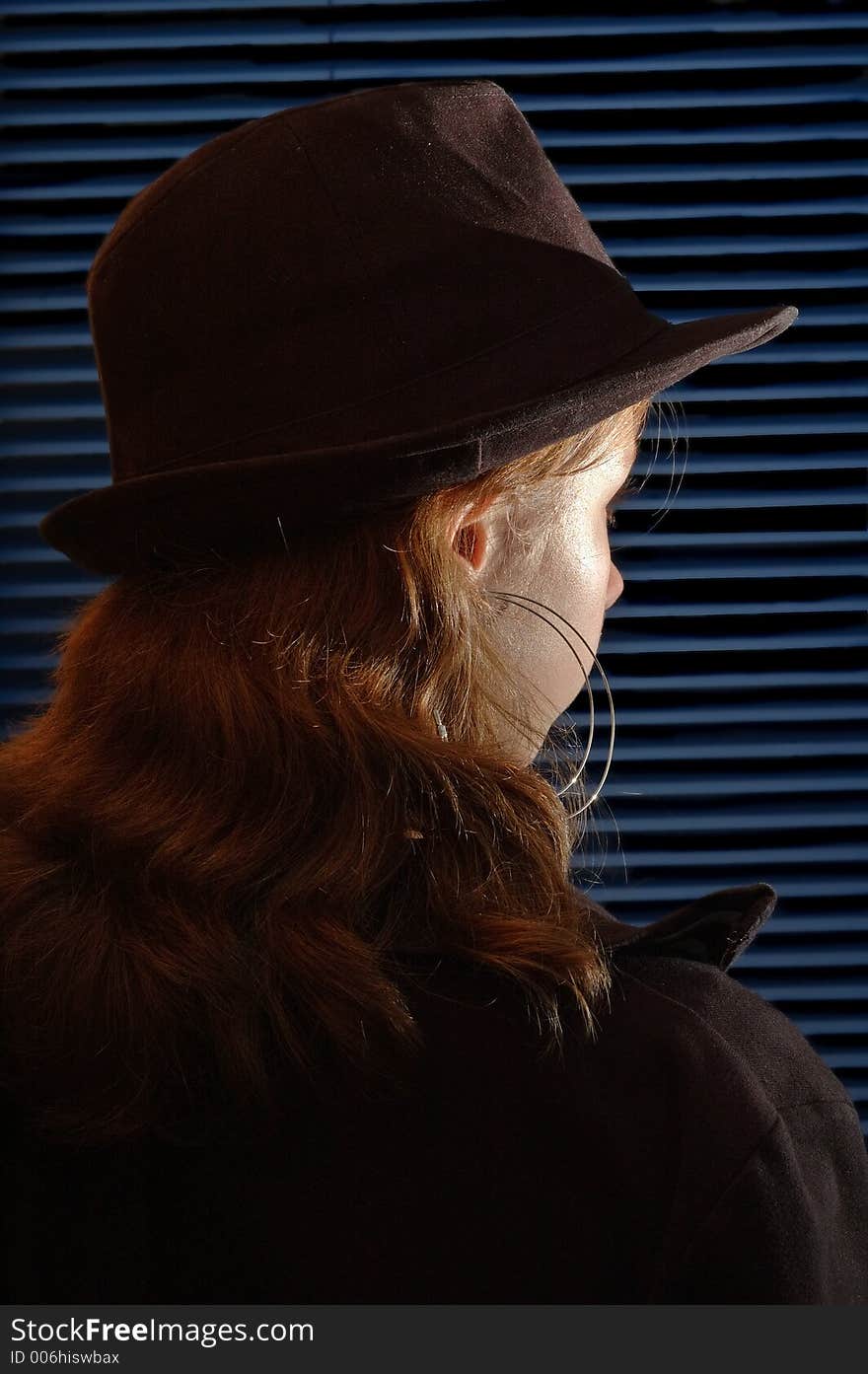 Young girl with a hat in front of a closed venitian blind. Young girl with a hat in front of a closed venitian blind.