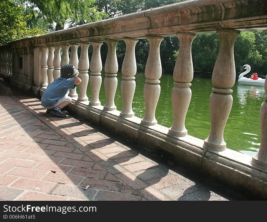 A boy watching traffic on a river. A boy watching traffic on a river