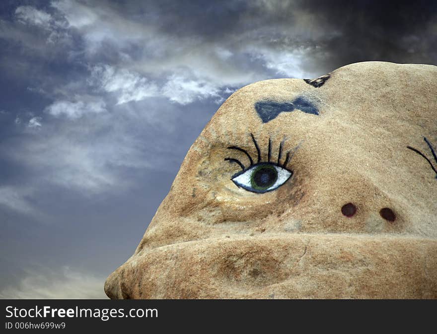 A face painted on a rock with spooky sky. A face painted on a rock with spooky sky