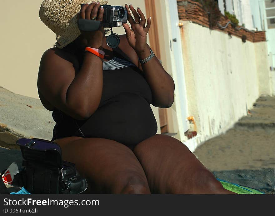 A lady is sitting on the beach making a video. A lady is sitting on the beach making a video.