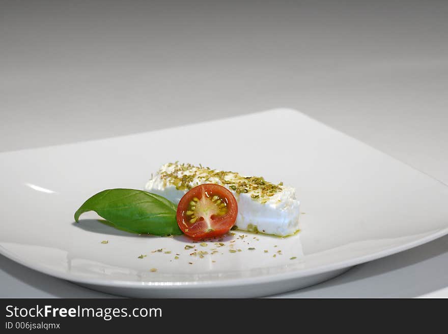 Feta, tomato and basil on white porcelain