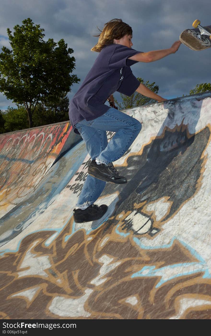 A young boy skateboarding up a ramp at a skate park. A young boy skateboarding up a ramp at a skate park