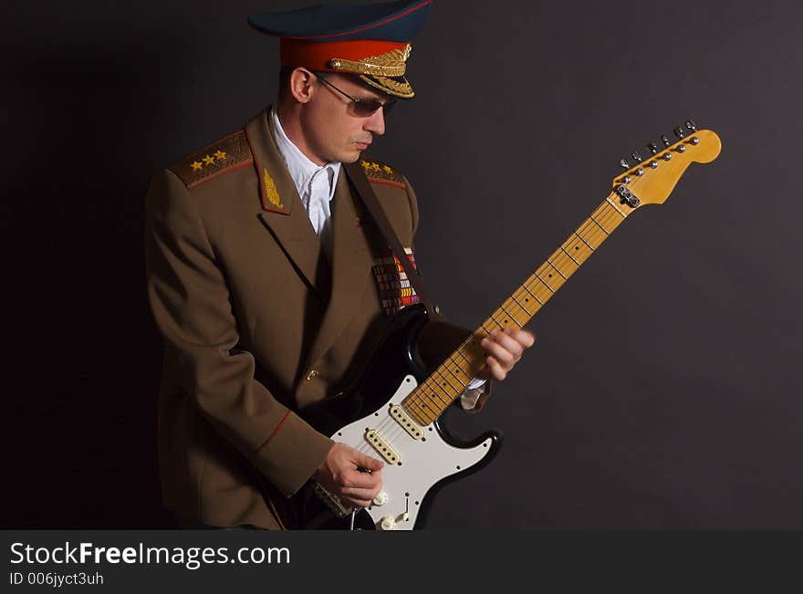 Portrait of a man dressed in a military uniform, playing an electric guitar. Portrait of a man dressed in a military uniform, playing an electric guitar