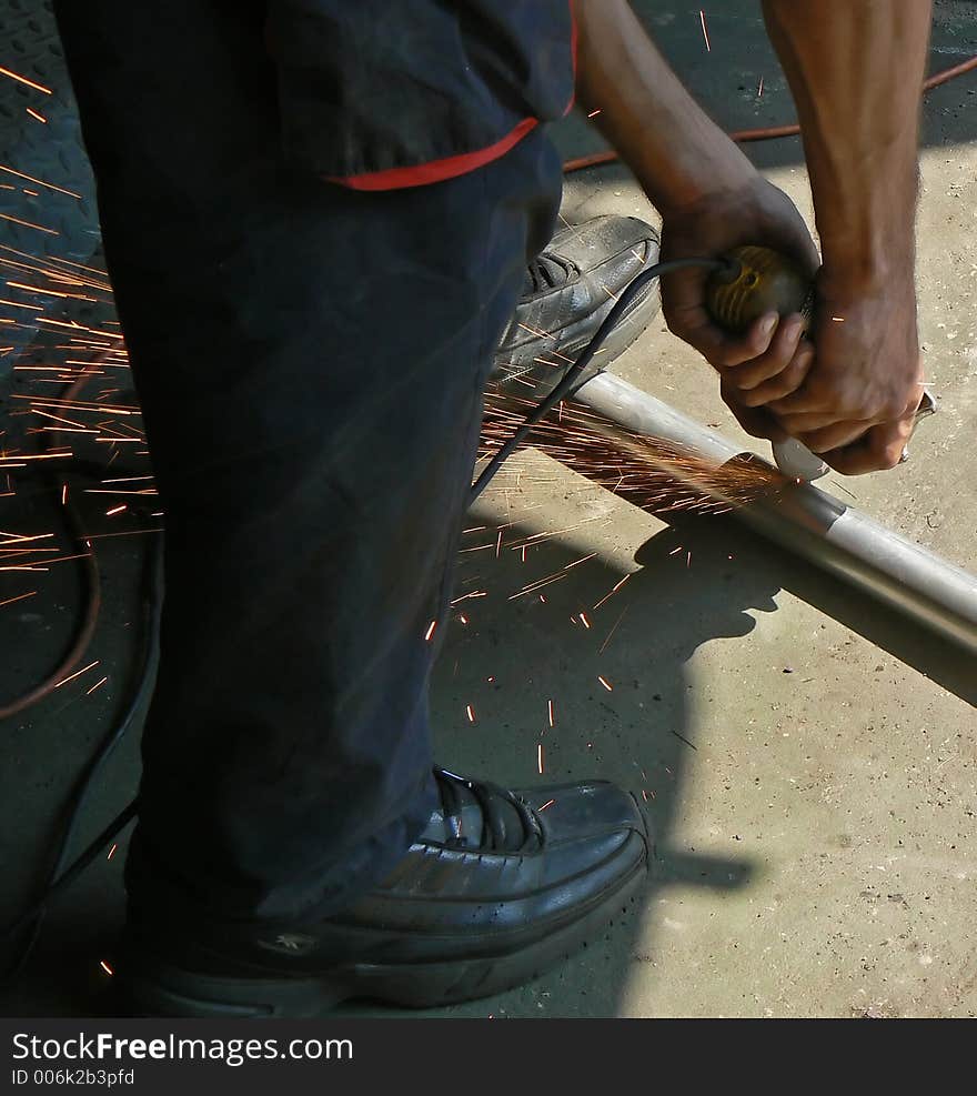 A worker grinding and cutting a pipe. A worker grinding and cutting a pipe