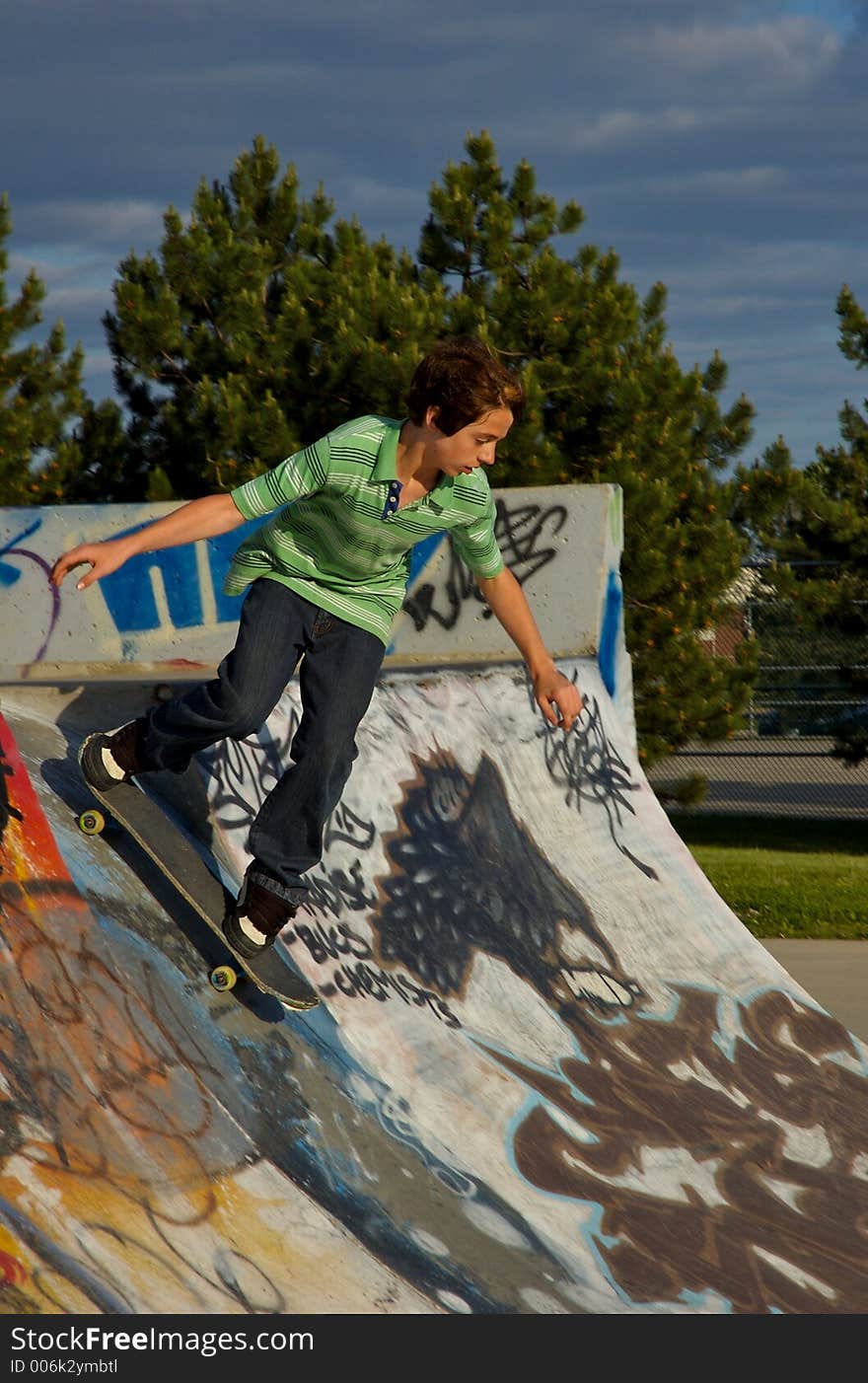 A young boy skateboarding up a ramp at a skate park. A young boy skateboarding up a ramp at a skate park