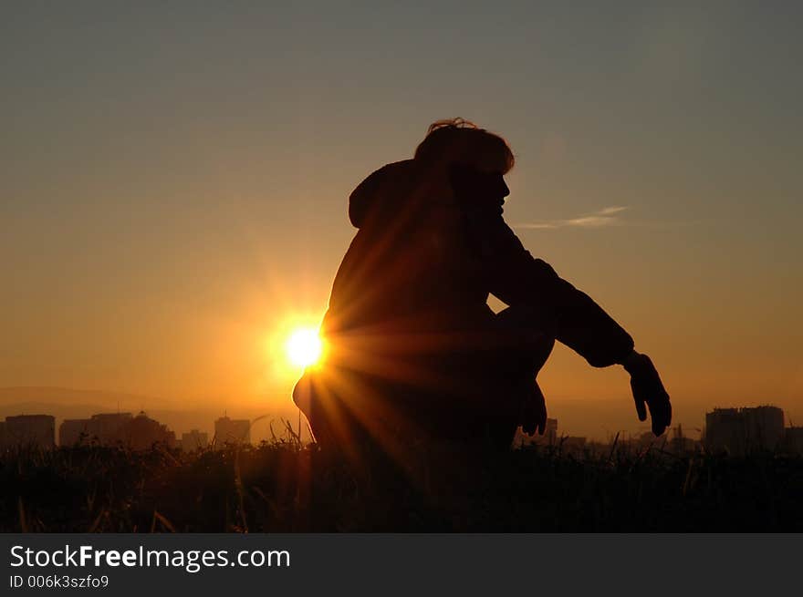 Girl sitting on the hill, watching the nightfall over the city. Girl sitting on the hill, watching the nightfall over the city