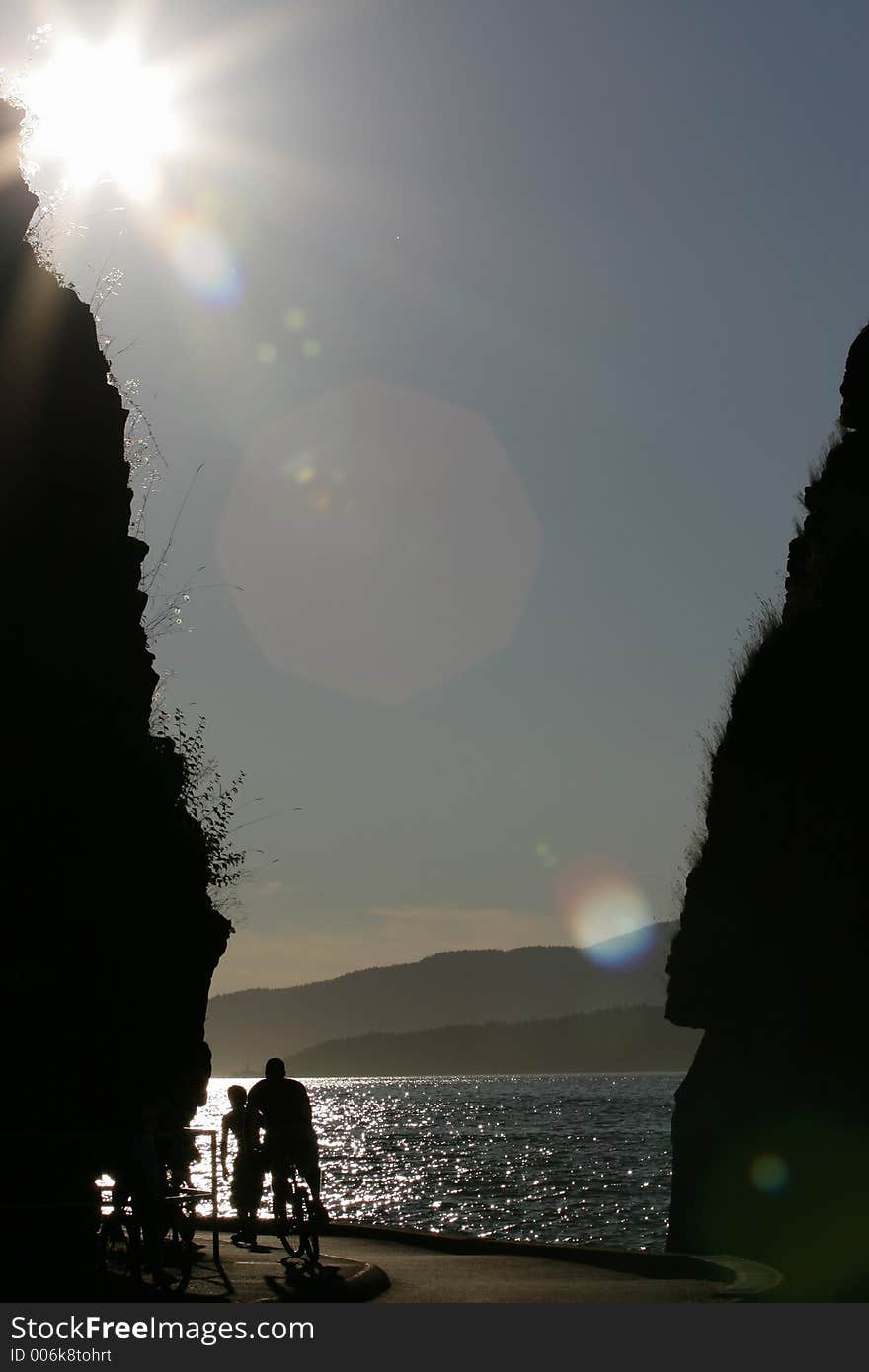 Cyclist cycling between rocks toward twilight as silouettes. Cyclist cycling between rocks toward twilight as silouettes.