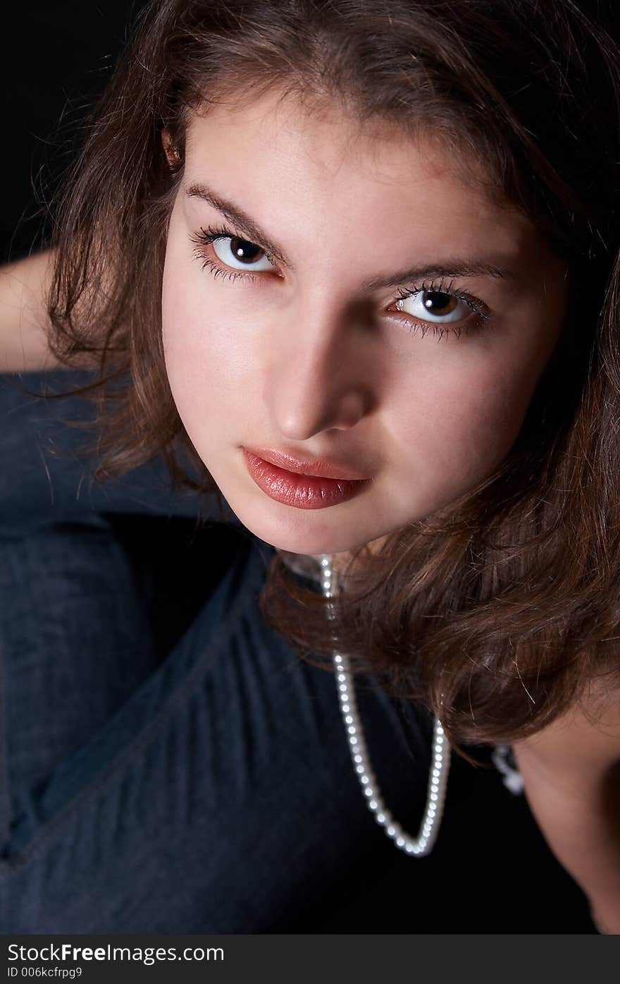 Girl with pearls and jeans looking up at the photographer. Girl with pearls and jeans looking up at the photographer