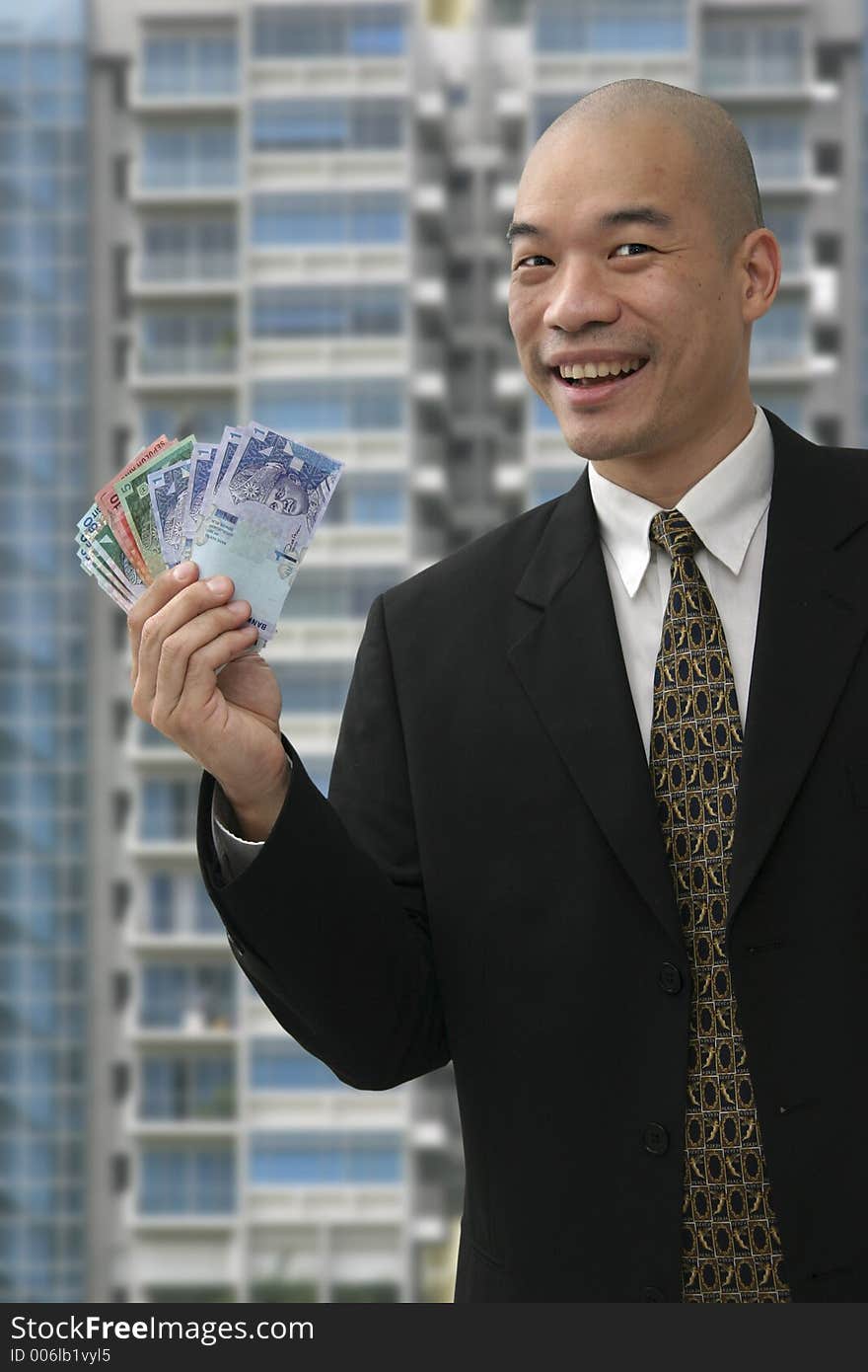 Chinese business man holding up money with building in the background. Chinese business man holding up money with building in the background