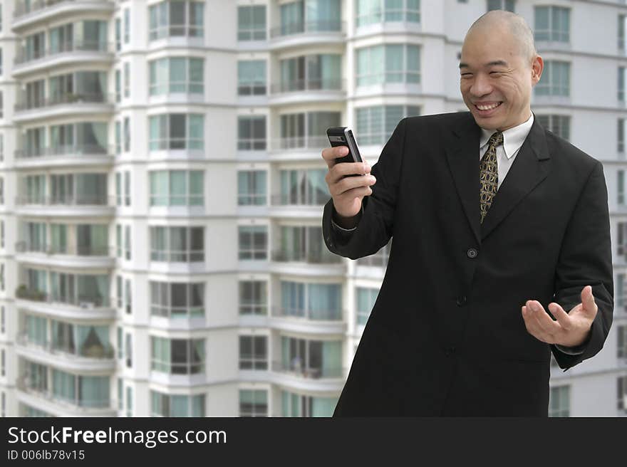 Chinese business man on a cellular phone with building in background. Chinese business man on a cellular phone with building in background