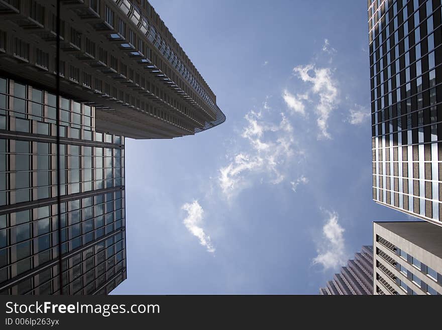 Picture taken from looking directly up into the sky between tall buildings. Picture taken from looking directly up into the sky between tall buildings