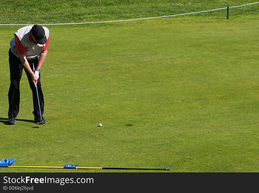 Golfer putting the ball into the hole in a tournament, ball heading towards hole. Golfer putting the ball into the hole in a tournament, ball heading towards hole