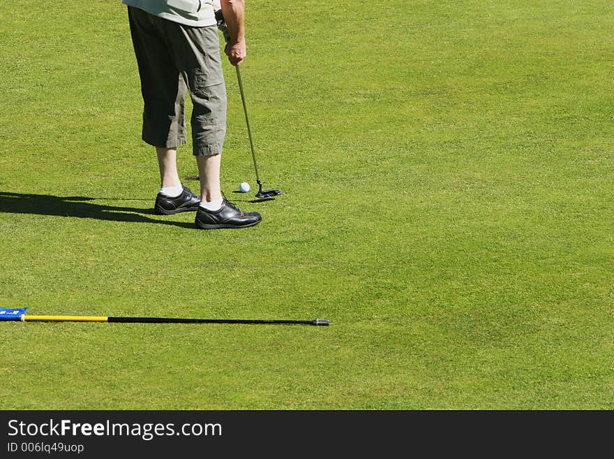 Golfer putting a short shot into the hole on a golfcourse. Golfer putting a short shot into the hole on a golfcourse