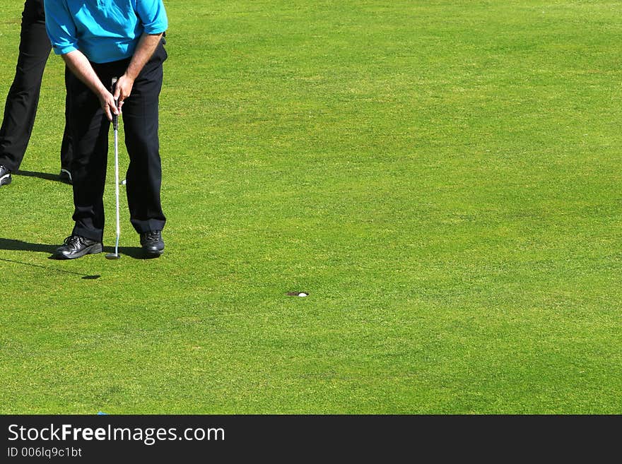 Golfer putting the winning shot on a golf tournament, golfball falling into the hole. Golfer putting the winning shot on a golf tournament, golfball falling into the hole