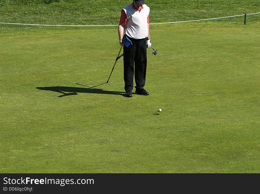 Golfcourse on a sunny day, golfers playing on the greens. Golfcourse on a sunny day, golfers playing on the greens