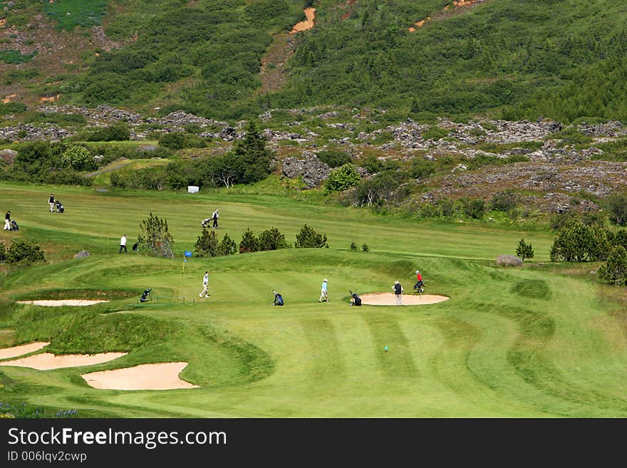 A green golfcourse on a sunny day, people on the greens playing golf. A green golfcourse on a sunny day, people on the greens playing golf