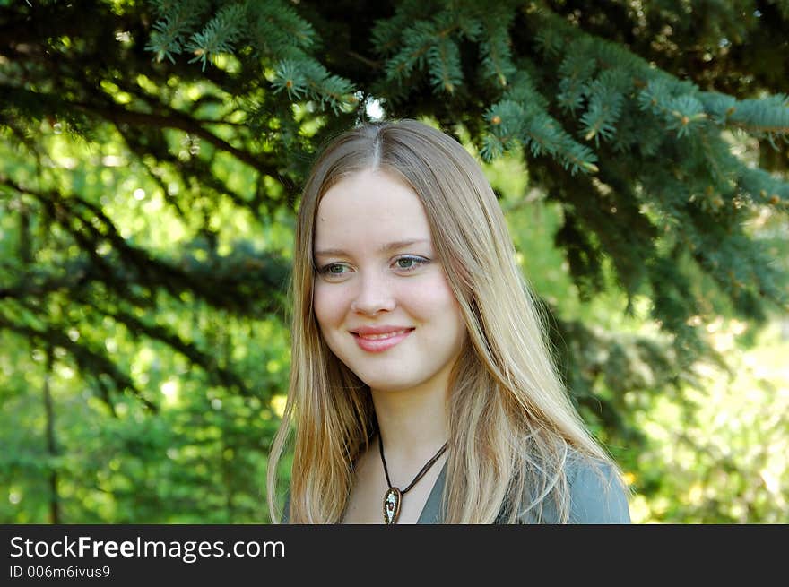 Beautiful girl in park at pines background